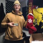 soldier holds the stocking filled with supplies sent to him by the desert angels